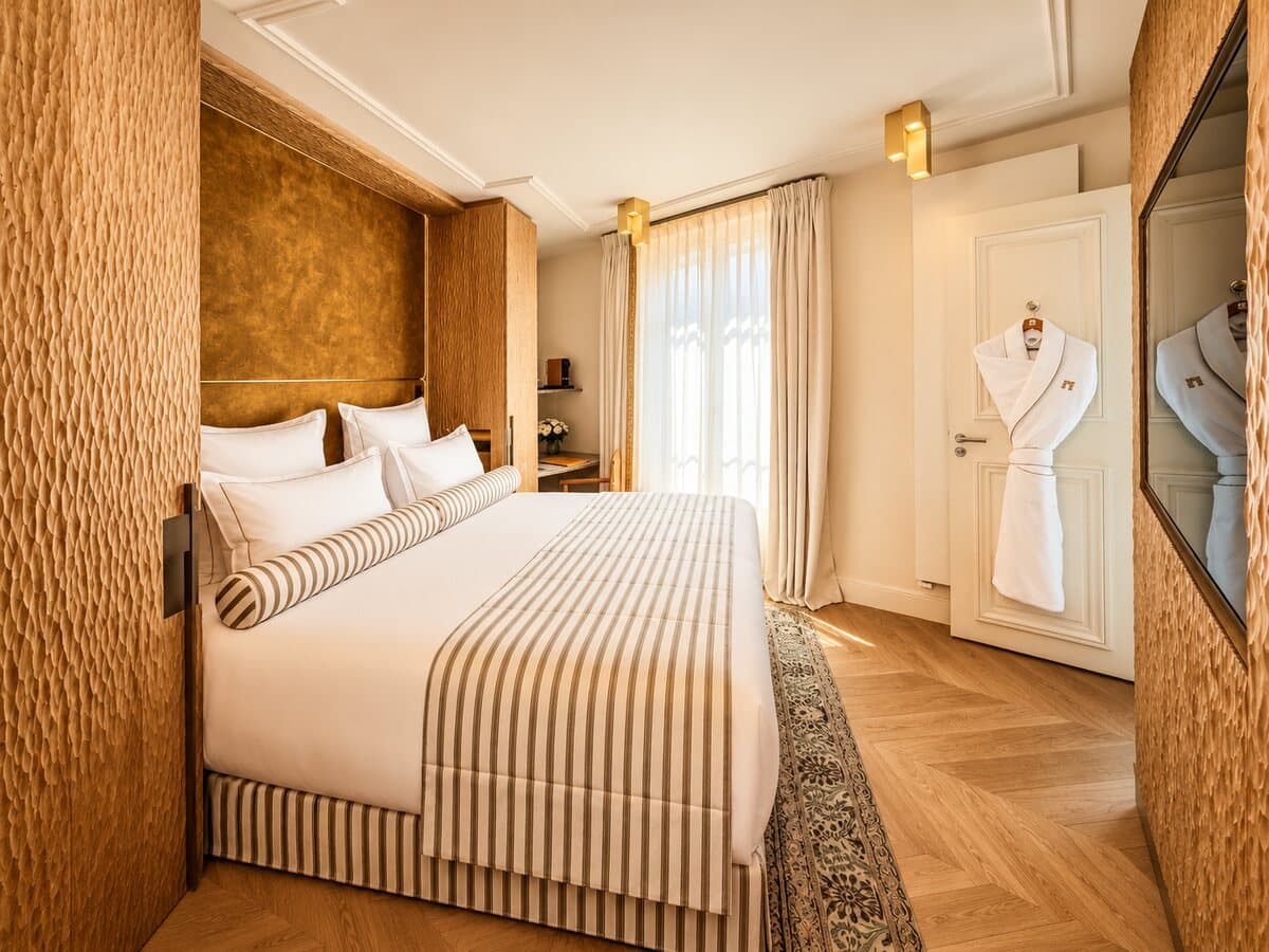 Kingsize-Bett des Deluxe-Zimmers und Bademantel am Eingang