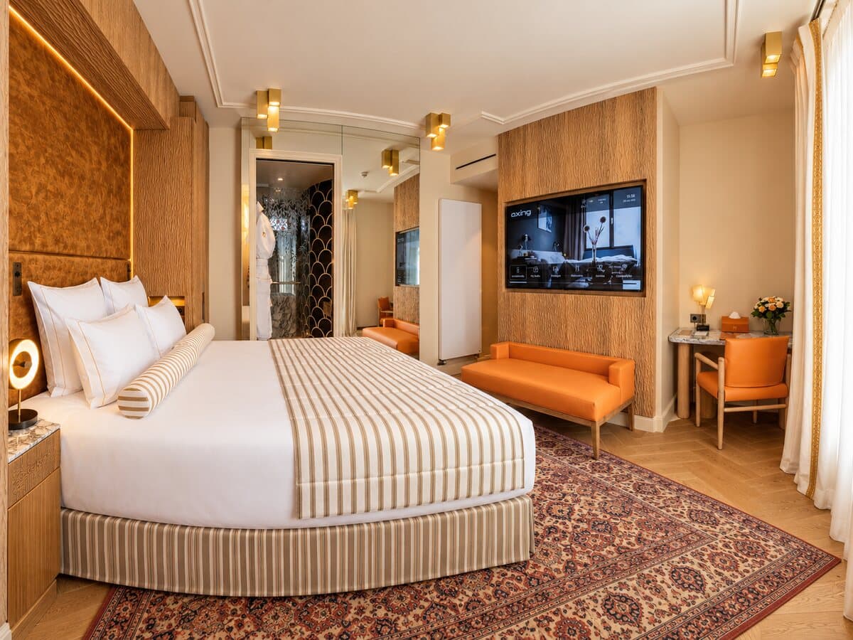 Deluxe-Zimmer mit Balkon: Kingsize-Bett, orangefarbene Sitzbank und Schreibtisch
